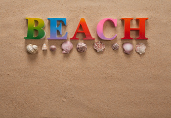 top view of beach written in colorful letters decorate with shellfish on the beach with copy space