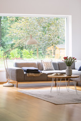 Large, industrial style floor lamp above an elegant sofa in a white and natural, scandinavian...