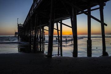 Fototapeta na wymiar Playing in the ocean by Newport beach pier at sunset