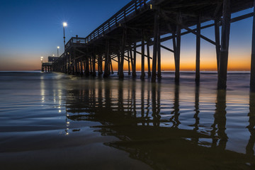 Fototapeta na wymiar Sun setting at dusk behind the Newport beach pier California