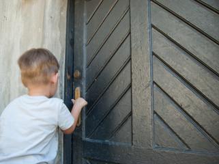 A little boy in front of a closed door.