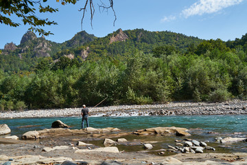 Image of a man fishing trout on a mountain river.