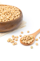 Soybeans in wooden bowl and spoon putting on linen and white background.