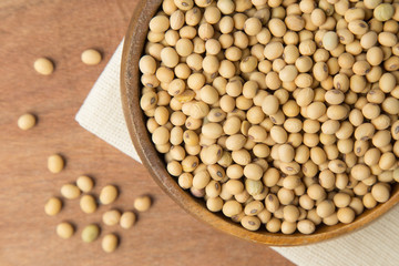 Soybeans in wooden bowl putting on linen and wooden background.