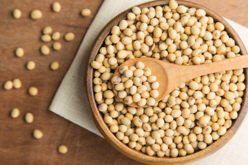 Soybeans in wooden bowl and spoon putting on linen and wooden background.