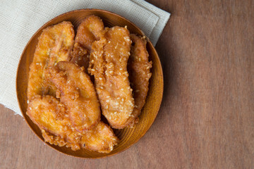 Fried bananas in wooden plate on white linen, Kluay Tod - Thai dessert.