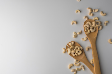 Piles of cashew in wooden spoones on white background. Nuts for health. Selective focus