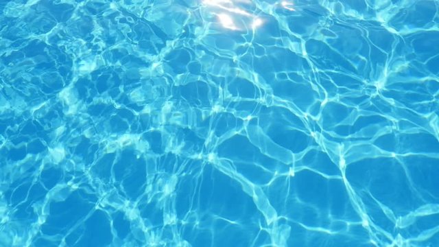 A gorgeous view of cyan-blue waters in a swimming pool with sparklinggrid shifting its shape cheerfully in summer in slow motion