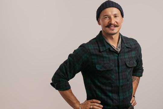 Portrait of kind cheerful smart professional friendly expert handsome handyman wearing knitted hat standing isolated on gray background copyspace