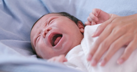 New born baby crying with hand comforting