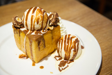 honey toast with vanilla ice cream and whiping cream topped with chocolate sauce on white dish. sweets bread and dessert. high calories from sugar. image for background, wallpaper and copy space.