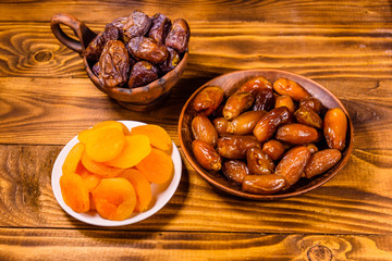 Date fruits and dried apricots on wooden table