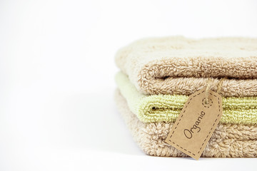 Fototapeta na wymiar Pile of organic cotton bath towels on white background. Eco textile tag. Copy space
