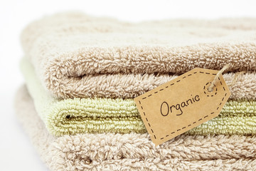 Fototapeta na wymiar Pile of organic cotton bath towels on white background. Eco textile tag.
