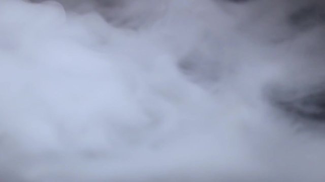 Cigarette smoke spreads on a black background