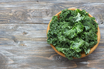 Fresh green curly kale leaves on a wooden table. selective focus. free space. rustic style. healthy vegetarian food