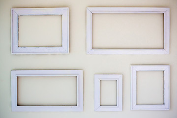 Blank white photo frames hang on the white cement wall. many photo frames on the white background.