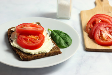 Dense rye bread with creamy cheese and tomato slices