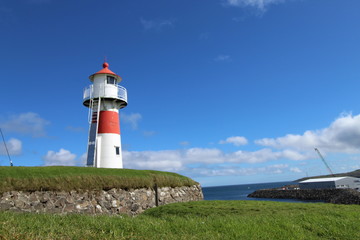 Fototapeta na wymiar Red and white lighthouse in Torshavn, faroe islands. Sunny summer day