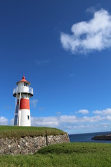 Fototapeta na wymiar Red and white lighthouse in Torshavn, faroe islands. Sunny summer day