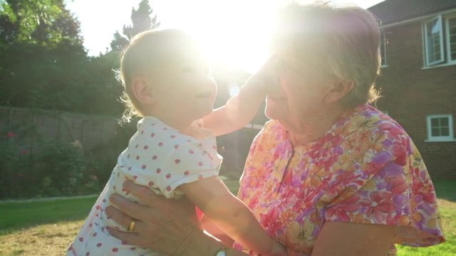 Portrait of a senior caucasian woman with her grand daughter in her garden backlit by the sun