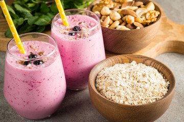 Glasses of berry smoothie with nuts, mint, blueberry, blackberry, raspberry, and yogurt on wooden table. Weight loss and diet concept. 