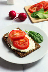 Dense rye bread with creamy cheese and tomato slices