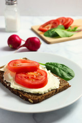 Dense rye bread with creamy cheese and tomato slices
