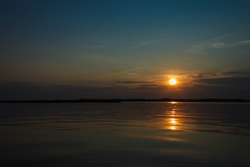 Obraz premium Sunset on the lake. Evening sky with beautiful clouds is reflected in the water of the lake