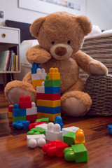 Kids toys background with teddy bear and colorful bricks.