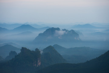 In the morning mountain range with visible silhouettes throug with fog