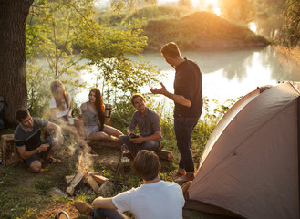 guy is telling campfire stories to the travelers in the nature at sunset