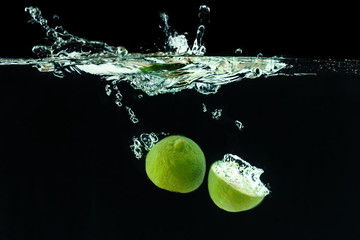 Fototapeta na wymiar Fresh lime dropped into water with splash