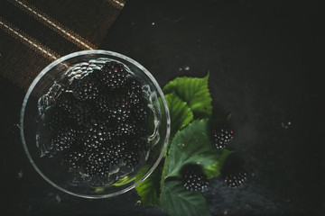 blackberries in a plate on a dark table