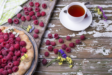 Sweet delicious freshly baked homemade French Country Pie with berries with cup of black tea on a wooden background,