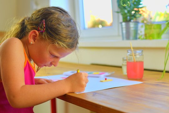Cute little girl painting picture of house. Selective focus, small DOF
