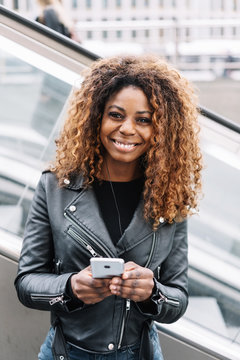Cheerful black woman using mobile phone