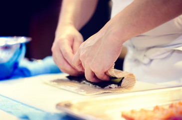 Japanese chef at work preparing delicious sushi roll