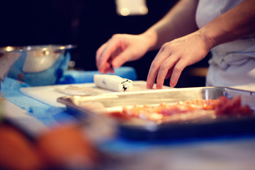 Fototapeta na wymiar Japanese chef at work preparing delicious sushi roll