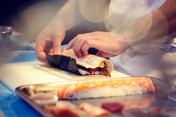Japanese chef at work preparing delicious sushi roll