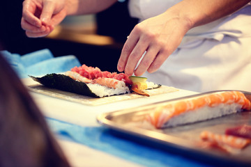 Obraz na płótnie Canvas Japanese chef at work preparing delicious sushi roll