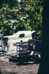 Woman working on tablet at table in sunny forest.
