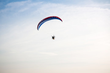 Adventure man active extreme sport pilot flying in sky with paramotor engine glider parachute. Paramotor flying on the sky at sunset. 