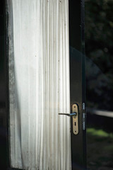 Door with white curtain in sunlight.