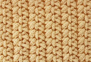Background texture beige pattern. Knitted fabric made of cotton or wool. Close-up, selective focus, top view, copy space.