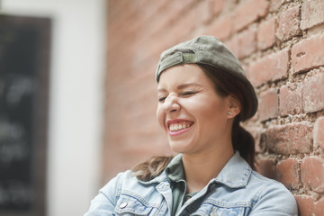 Frau mit Kappe an einer Backsteinwand