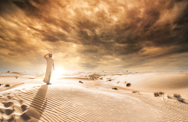 Fototapeta premium Mężczyzna ubrany w tradycyjne stroje ze Zjednoczonych Emiratów Arabskich spędzający czas na pustyni