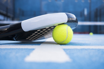 Paddle tennis court, net, racket, balls.
