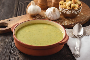 Broccoli cream soup with croutons on wooden background.
