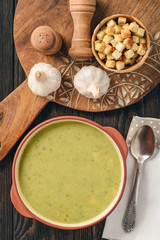 Broccoli cream soup with croutons on wooden background.